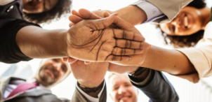 people shaking hands in a circle photographed from below